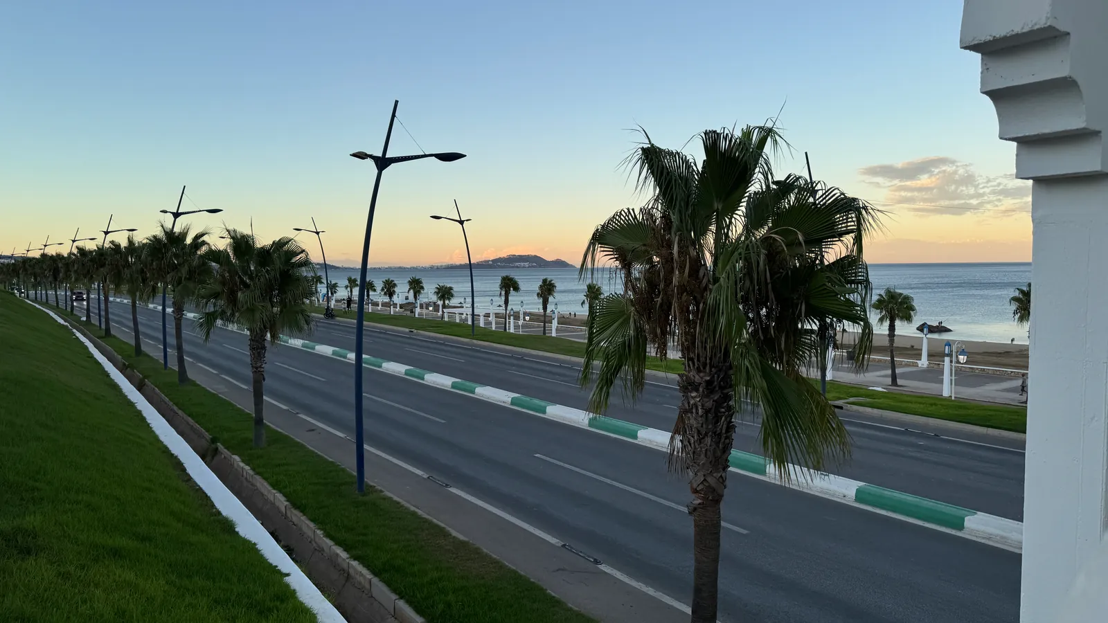 La route côtière bordée de palmiers longe la plage Riffiine, au nord de Tétouan, en fin de journée