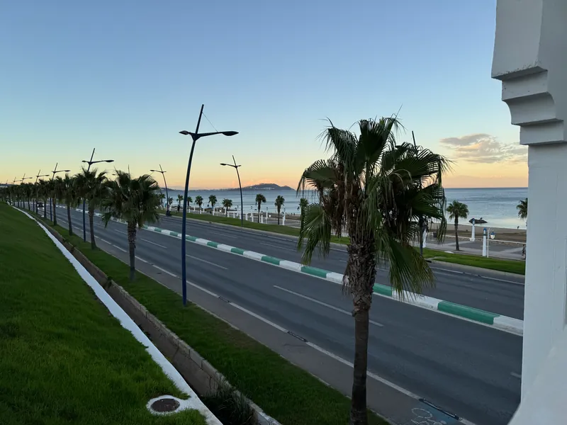 La route côtière bordée de palmiers longe la plage Riffiine, au nord de Tétouan, en fin de journée