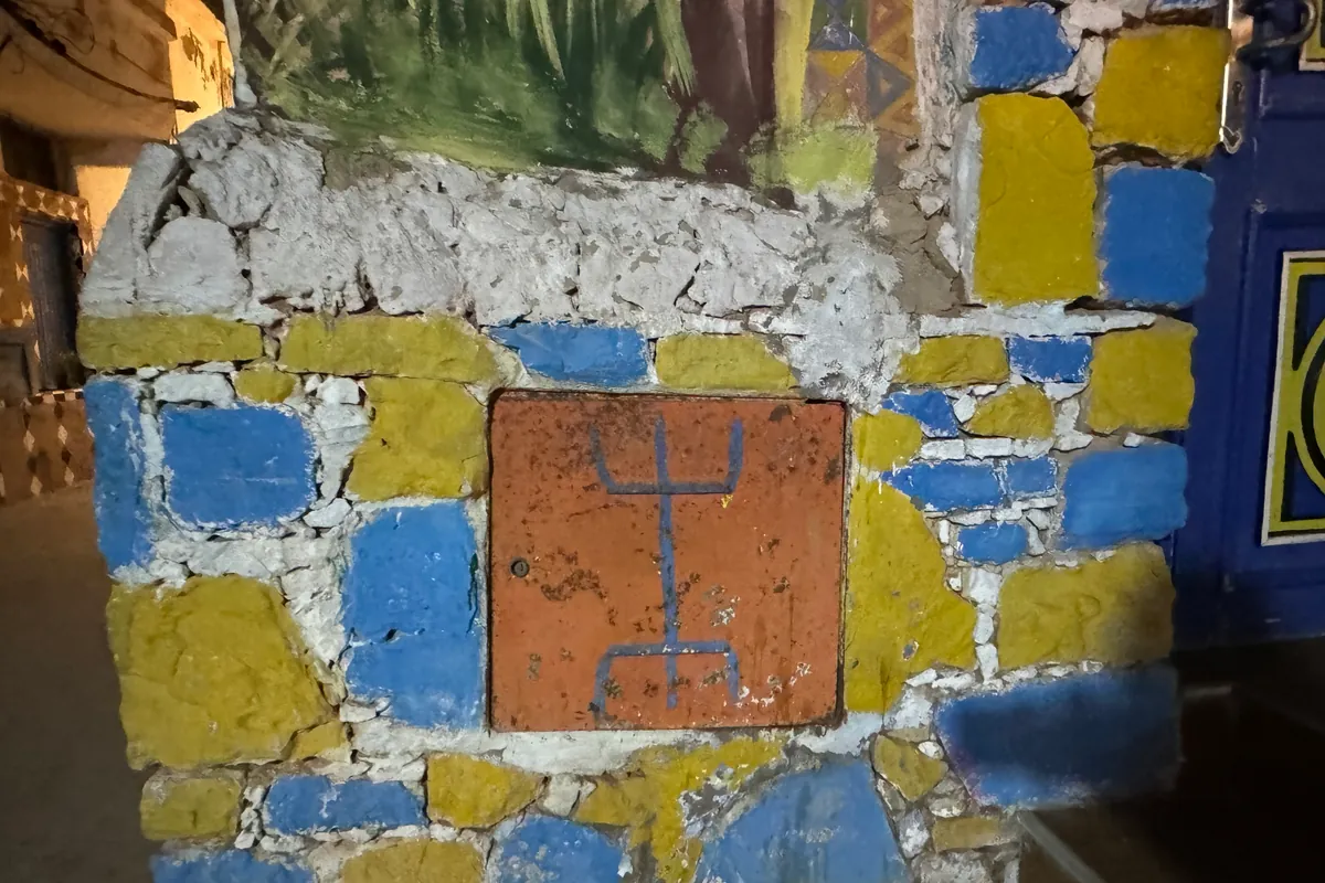 Mur peint en bleu et jaune, orné du yaz, le symbole amazigh, dans une ruelle de Taghazout (octobre 2024)