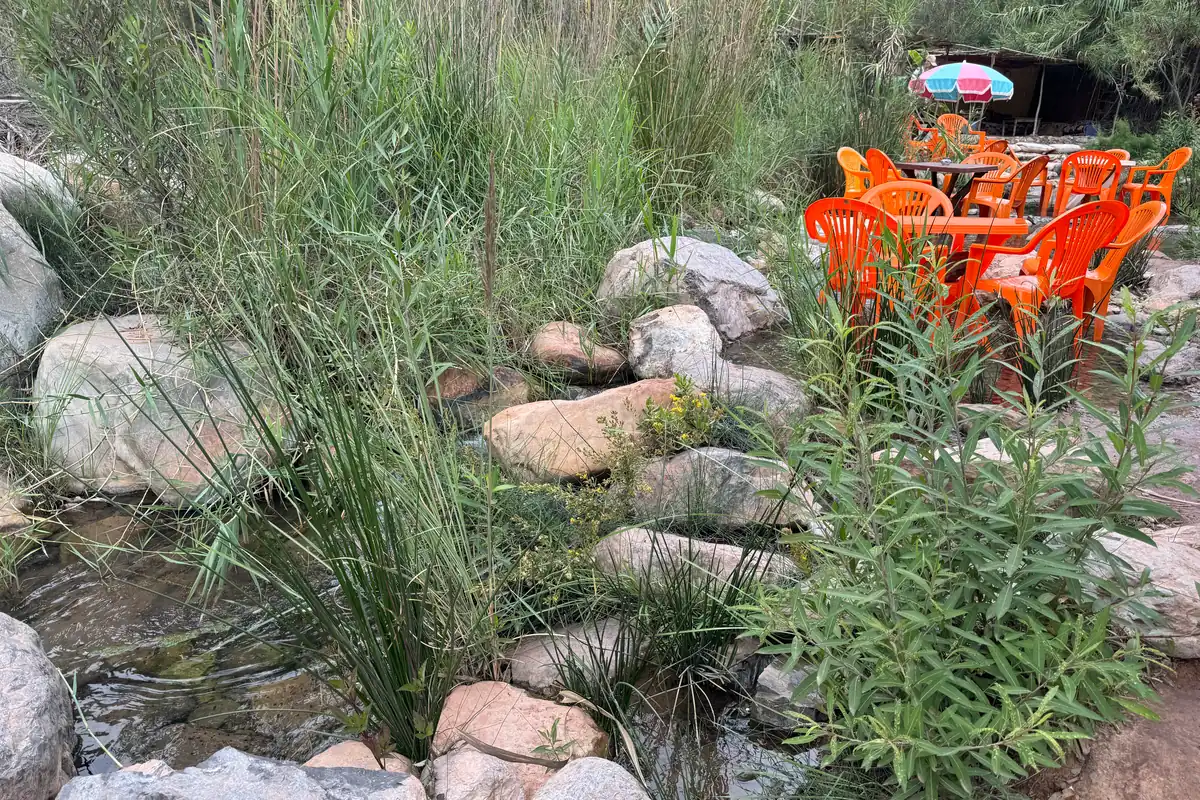 L'oued entre les rochers, et les chaises orange d'un café au bord de l'eau (octobre 2024)