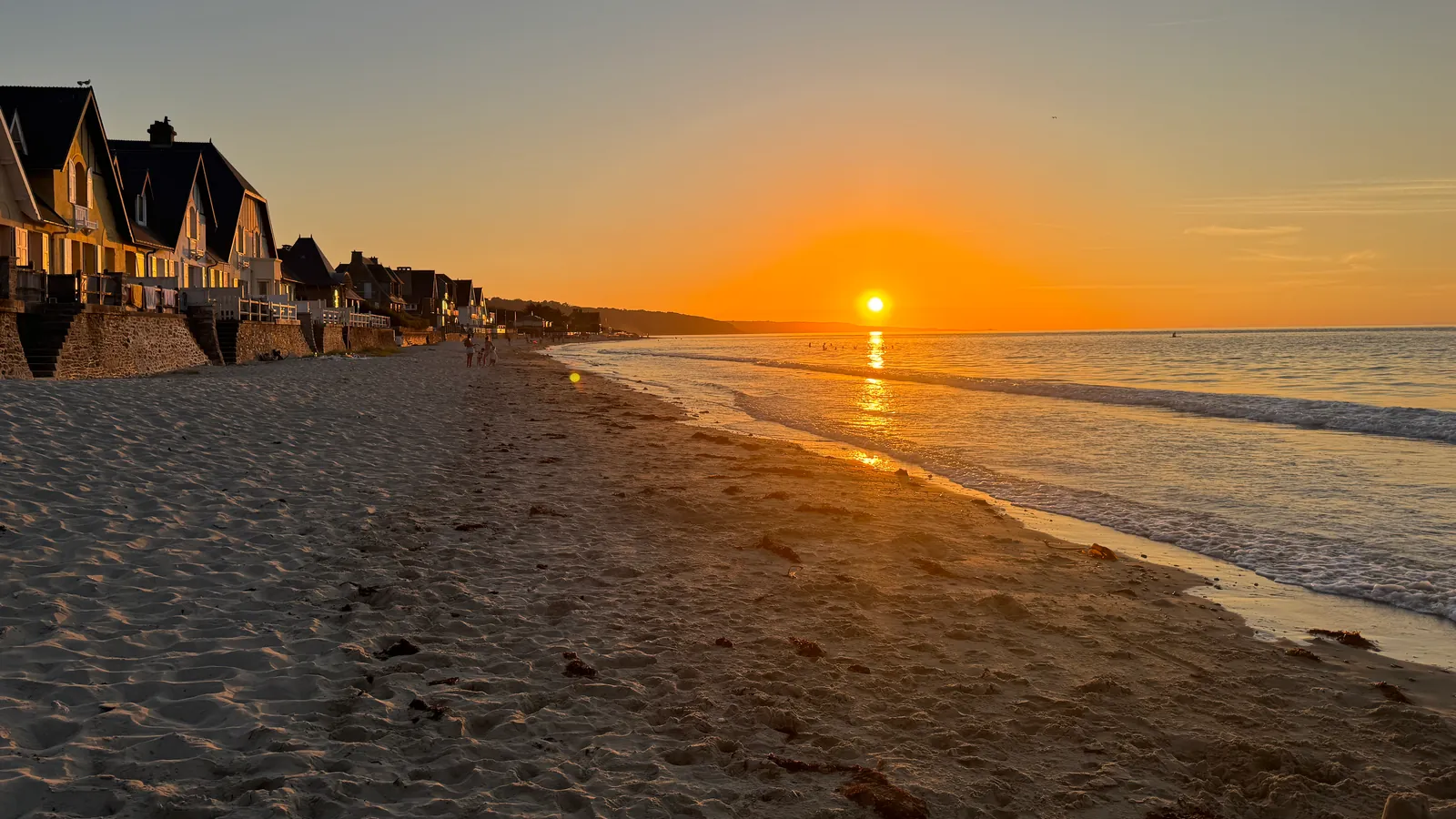 Le soleil couchant au-dessus de la mer, sur la plage d'Urville-Nacqueville bordée de villas