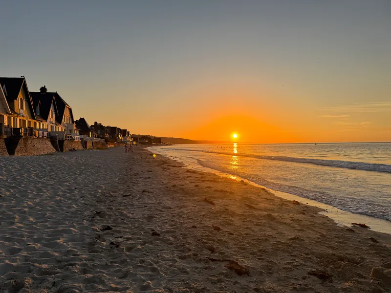 Le soleil couchant au-dessus de la mer, sur la plage d'Urville-Nacqueville bordée de villas